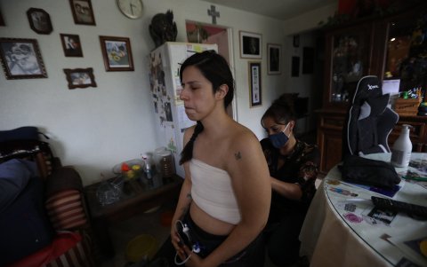 Sandra Monroy (i), recibe ayuda de Gina Ramírez (d), en su habitación el 30 de septiembre de 2021, en la Ciudad de México, tres meses después de que se le practicara una masectomía bilateral a causa del cáncer de mama que padecía.