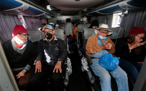 Venezolanos abordan un bus que los llevara al aeropuerto Mariscal Sucre hoy viernes, frente al consulado de su país en Quito.