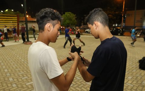 Equipándose. Un joven le ayuda  a colocar las vendas a su amigo, previo al inicio de las clases de kick boxing.