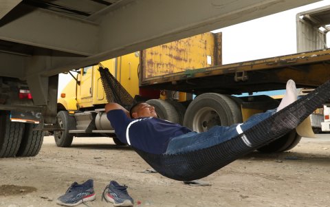 Sin zapatos y en la hamaca bajo la plataforma de su camión, Enrique Acebo está listo para dormir un rato, hasta que le entreguen la mercadería que debe transportar.