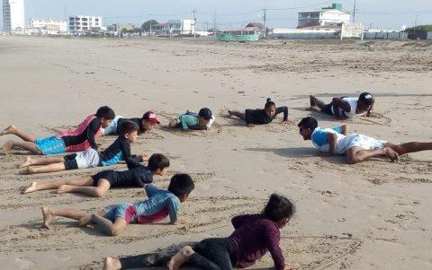 Víctor dirige una clase de surf en la playa antes de ingresar al mar.