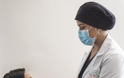 Una profesional de salud procede con un hisopo a tomar de la paciente una muestra de sus fosas nasales.