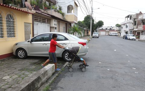 Este niño, que pasea a su hermanito en un coche, debe bajar de la vereda ante el obstáculo que le produce un automotor mal parqueado.
