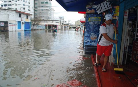El propietario de un negocio internta evacuar el agua que entró a su local