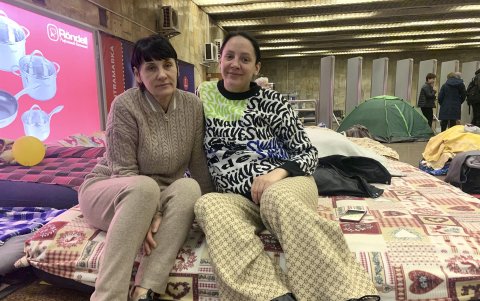 Dos mujeres sonríen a la cámara en el interior de la estación de metro 'Héroes de Dnipra', este lunes en Kiev (Ucrania).