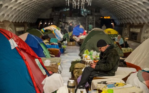 Con lo poco. Un hombre revisa su celular sentado en la camilla en la que ha desarrollado su vida en casi dos meses del asedio ruso a su ciudad, en Ucrania.