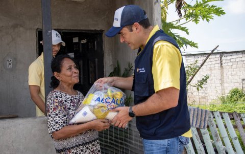 El alcalde Juan José Yúnez entrega una ración de alimentos a una habitante de Samborondón.