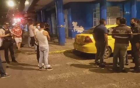 Policías junto al taxi atacado por los maleantes y cuya pasajera fue alcanzada por las balas.