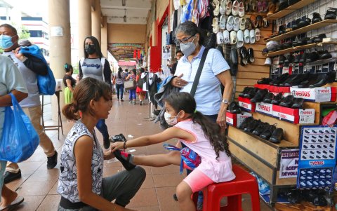 Atención. Una mujer le prueba a su pequeña hija el calzado con el que aspira retorne la menor a sus clases presenciales.