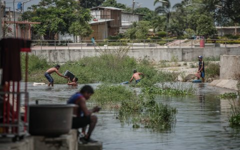 Un grupo de venezolanos atraviesan un riachuelo en la frontera entre Ecuador y Perú.