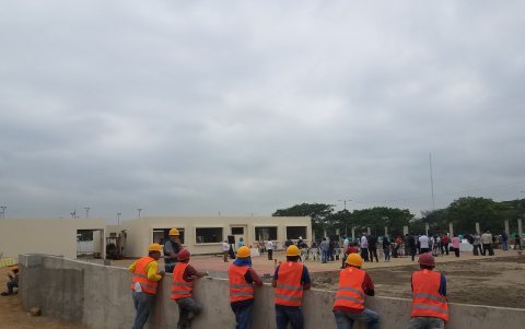 Un grupo de trabajadores que construye la unidad educativa José Joaquín de Olmedo observa los preparativos para la visita del presidente Lasso.