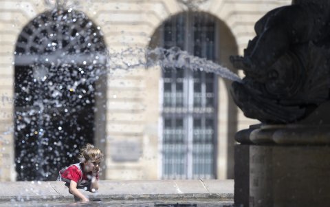 Un niño se rocía con agua de la fuente en la Place de la Bourse, durante la ola de calor, en la ciudad francesa de Burdeos.