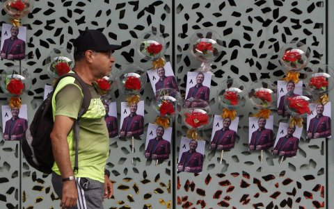 Un hombre camina frente a fotografías del cantante colombiano Darío Gómez.