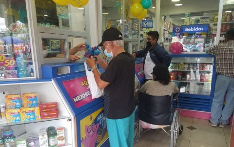 Segundo Luna, de 70 años, retira su insulina en la farmacia ubicada frente al Hospital Abel Gilbert. Al fondo, otro usuario hace lo mismo con los fármacos de una persona con movilidad reducida.
