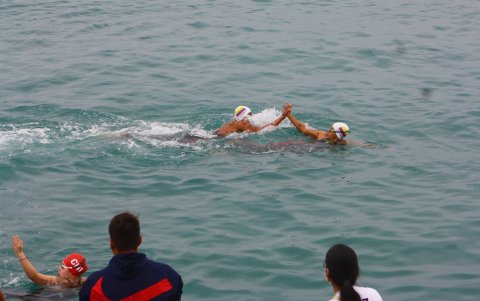 Dos nadadores tricolores chocan sus manos en el agua durante el último día de competencias en el torneo internacional de aguas abiertas.