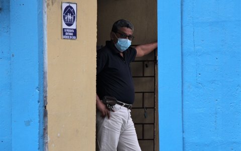 Un miembro del colegio vigila la puerta del local e impide al acceso de los padres de familia.