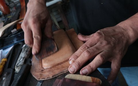Oficio. Un artesano pule lo que sería un estuche para celulares.