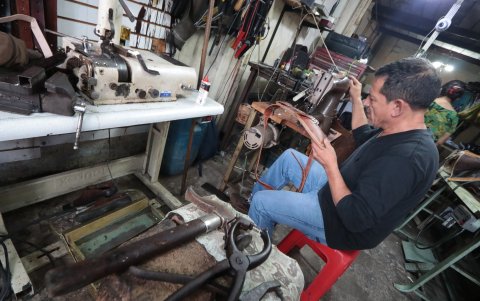 Destreza. Hugo Fernández mientras trabaja con un bolso en su taller, donde predominan cinturones y billeteras