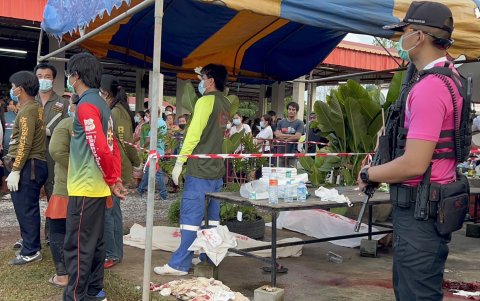 Policías armados observan cómo rescatistas recogen los cuerpos de las victimas del tiroteo.