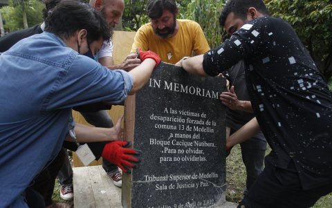 Un grupo de hombres instala una placa durante un acto de conmemoración de los 20 años de la Operación Orión el 14 de octubre de 2022 en Medellín.