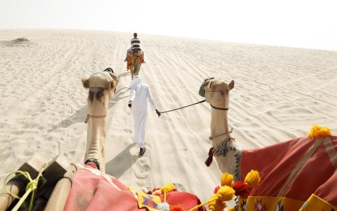 n camellero tira de varios camellos con turistas en el desierto de Qatar en una imagen tomada el 16/09/2022,