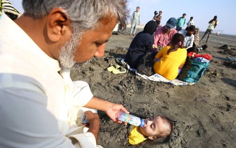 Un niño discapacitado es enterrado hasta el cuello en la arena durante el eclipse solar parcial creyendo que sus rayos pueden curar, en Karachi, Pakistán.