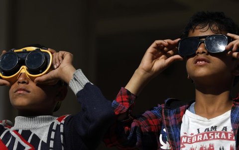 Los niños usan anteojos protectores para observar un eclipse solar parcial en Sana'a, Yemen.
