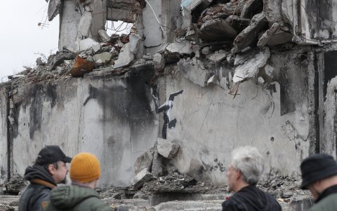 Kiev. Ucranianos se apuestan en los alrededores de una de las obras del británico Banksy, en la que aparece una gimnasta haciendo un ejercicio de cabeza entre las ruinas de un edificio bombardeado.