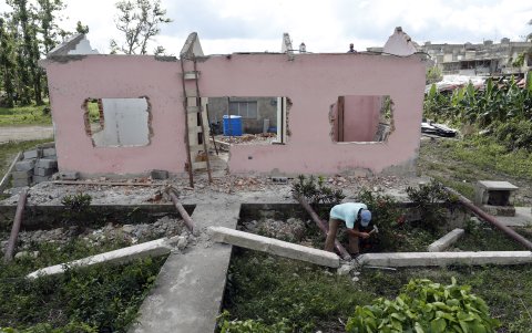 Trabajo. Un hombre obtiene hierro de una casa afectada por Ian.