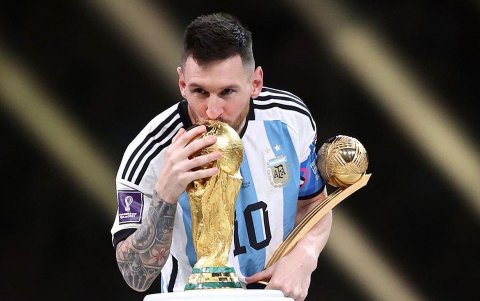 Lionel Messi besa la Copa del Mundo y sostiene el trofeo a mejor jugador del Mundial.