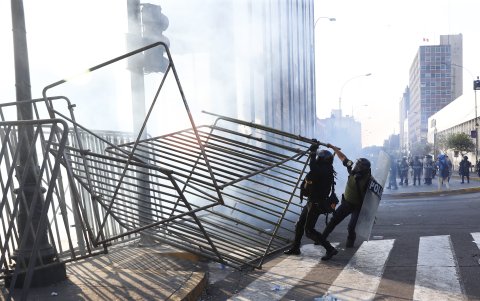 Lima. Policías tratan de instalar unas cercas durante enfrentamientos con manifestantes en una nueva marcha antigubernamental.
