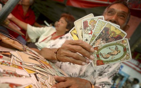 Un filipino, echador de cartas del Tarot para adivinar el destino de los transeúntes, en Manila. La cartomancia es una de las mancias adivinatorias.
