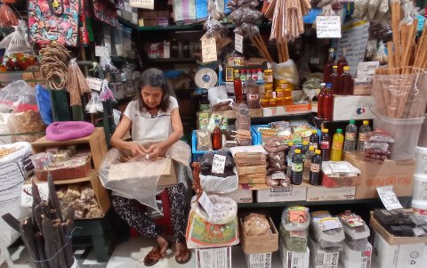 Una comerciante alista paquetes de canela para vender. El costo de cada uno es de un dólar.