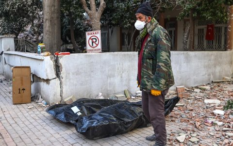 Un hombre de pie junto al cuerpo de una víctima del terremoto en el sitio de los edificios derrumbados después de un fuerte terremoto, en Hatay, Turquía, el 15 de febrero de 2023.