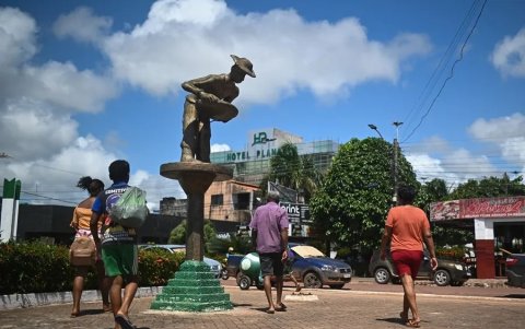 Varias personas caminan junto a una estatua que honra a los mineros informales a orillas del río Tapajós, el 13 de febrero de 2023, en Itaituba, estado de Pará (Brasil).