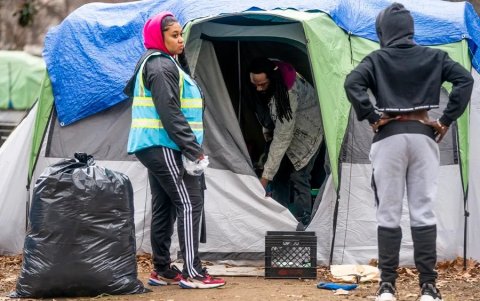 Un defensor de personas sin hogar alienta a un hombre a empacar sus pertenencias antes de que los miembros de un equipo de limpieza del Servicio de Parques Nacionales despejen el campamento.