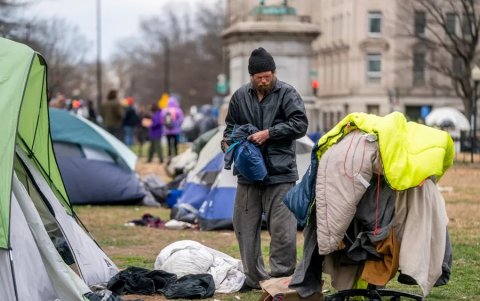 Un hombre sin hogar empaca sus pertenencias antes de que los miembros de un equipo de limpieza del Servicio de Parques Nacionales desalojen un campamento para personas sin hogar.