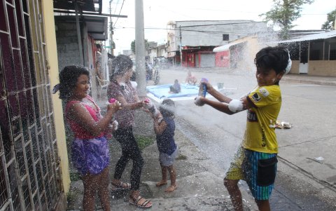 Niños y grandes juegan con espuma de carnaval entre familiares y amigos.