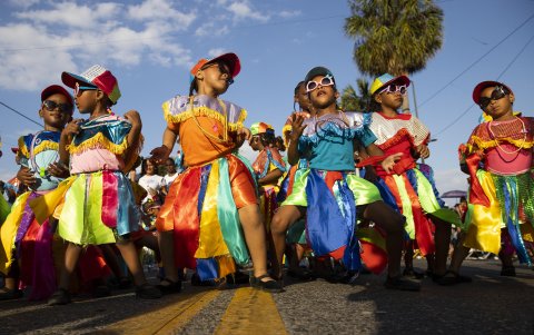 Niños y mayores ataviados con colores brillantes y grandes sonrisas participaron en el desfile que, posiblemente a causa del calor, tardó más de la cuenta en comenzar con respecto a las previsiones de los organizadores, la Unión Carnavalesca del Distrito (Ucadi) y el Ayuntamiento capitalino.