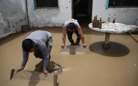 Personas limpian el lodo de una casa afectada por las lluvias este 15 de marzo de 2023, en el balneario de Punta Hermosa al sur de Lima (Perú).