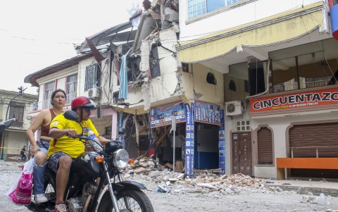 Una pareja en motocicleta pasa frente a una edificación del cantón Pasaje afectada por el terremoto del 18 de marzo de 2023, días después del suceso.