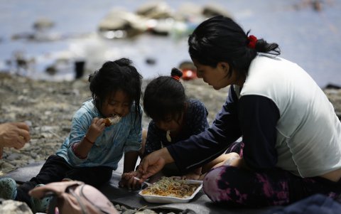 Realidad. Una migrante ecuatoriana come junto a sus hijas en la selva, mientras esperan ser trasladadas en canoa desde la Quebrada del León.