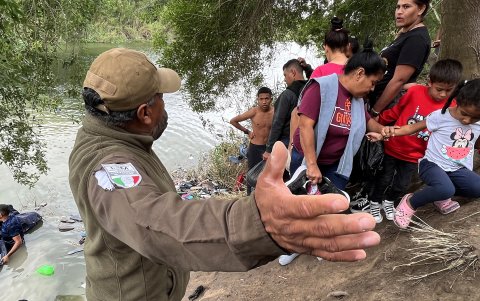 Un integrante del Instituto Nacional de Migración (INM) habla con un grupo de migrantes para que no crucen el Río Bravo  , en la ciudad de Matamoros en Tamaulipas (México).