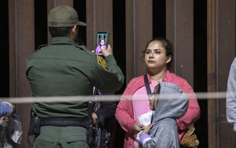 Una mujer migrante y su hija tienen su foto tomada por un agente de la patrulla fronteriza mientras son procesadas después de que cruzaron ilegalmente en los EE. UU.