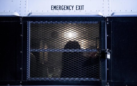 La silueta de un migrante se ve a través de la ventana enrejada de un autobús que lo llevará a un centro de procesamiento después de cruzar ilegalmente en los EE. UU., en Yuma.