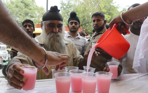Varias peronas toman un refresco para sofocar la ola decalor que enfretan Nueva Delhi