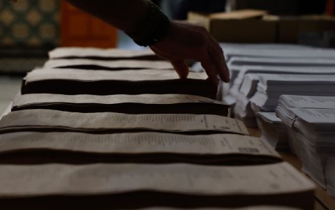 Un hombre escoge entre las papeletas para votar en el colegio Nuestra Señora del Buen Consejo, este domingo, durante las elecciones locales municipales y autonómicas