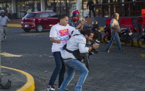 Fotografiá del 18 de abril de 2018 que muestra un miembro de la juventud sandinista (i) forcejeando con el reportero gráfico de la agencia de noticias AP Alfredo Zuniga (d), en Managua (Nicaragua).