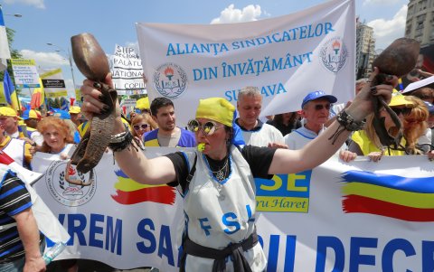 Un maestro rumano (C) hace sonar un silbato mientras hace ruido con dos cencerros durante una marcha de protesta sindical en Bucarest, Rumania, el 30 de mayo de 2023.