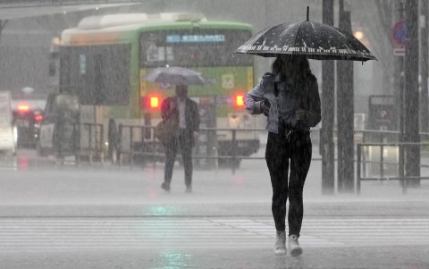 Una mujer joven camina bajo fuertes lluvias en Tokio, Japón, el 2 de junio de 2023. El aire cálido y húmedo generado por el tifón Mawar fluyó hacia el frente de la temporada de lluvias